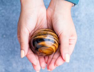 Frau hält Tigerauge Kugel